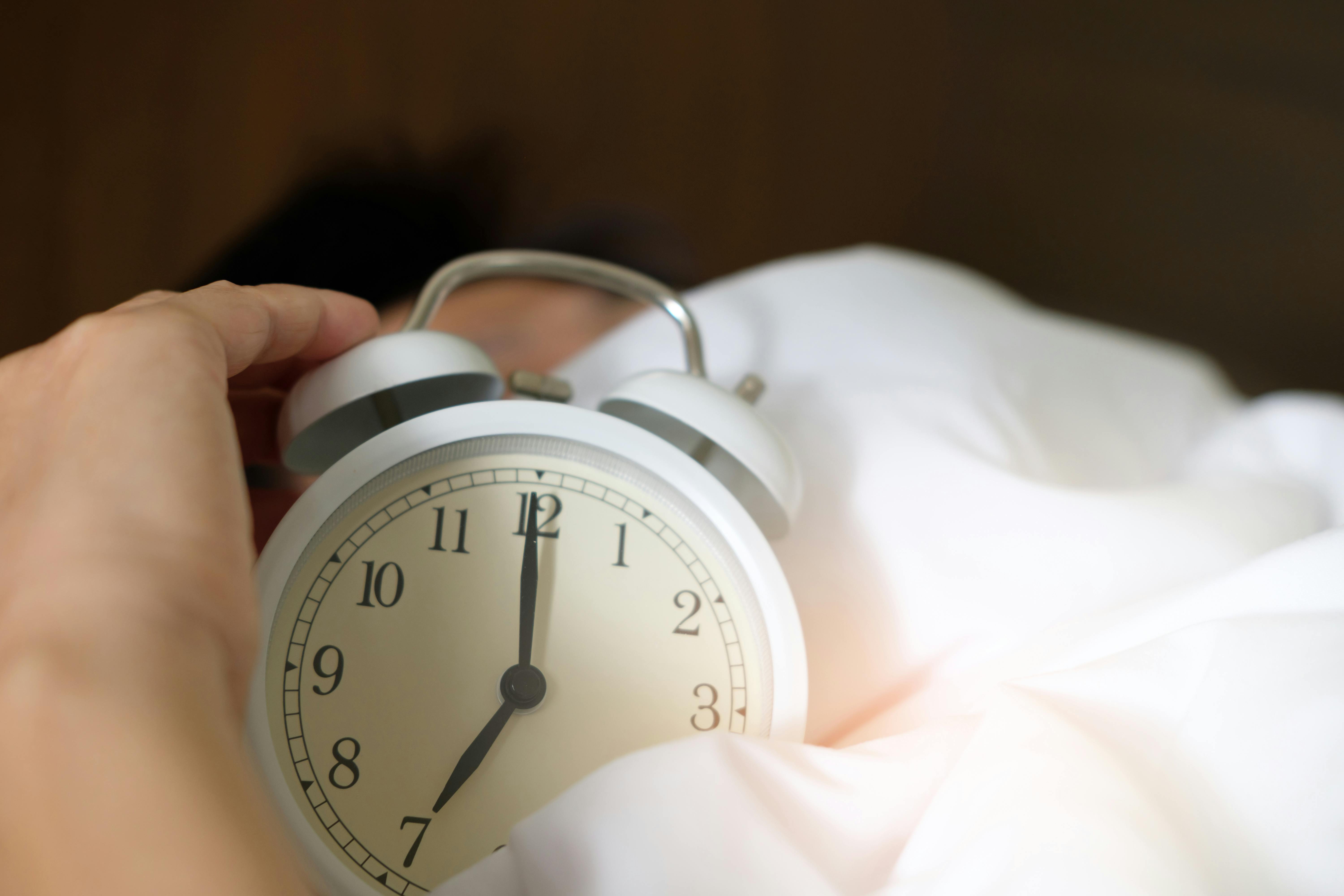 Photo of a man holding an alarm clock | Source: Pexels