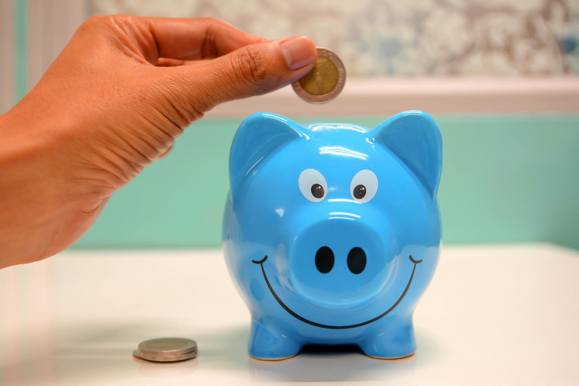 Person putting money in a piggy bank | Source: Pexels