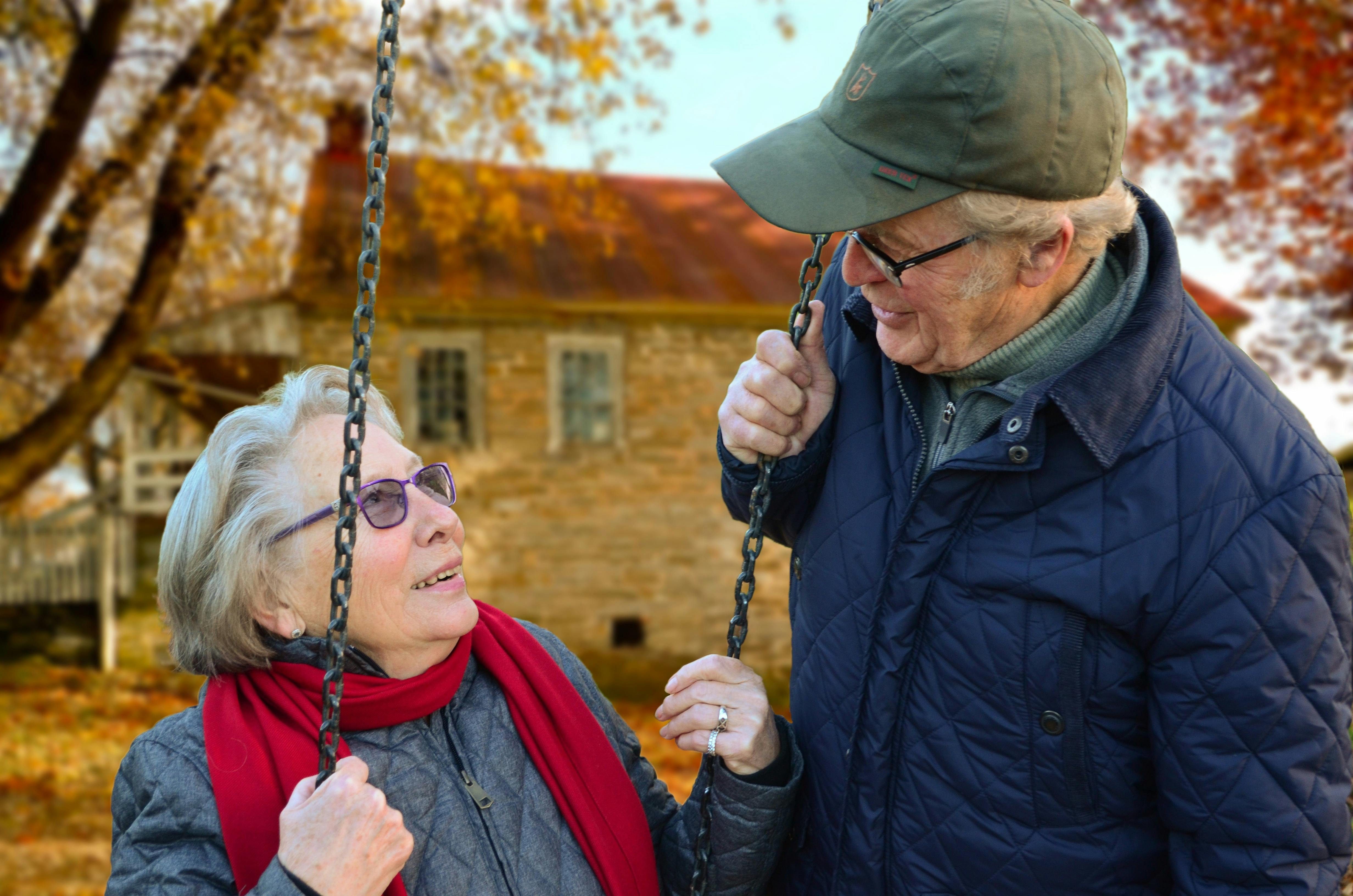 Woman sitting on a swing and man standing next to her | Source: Pexels