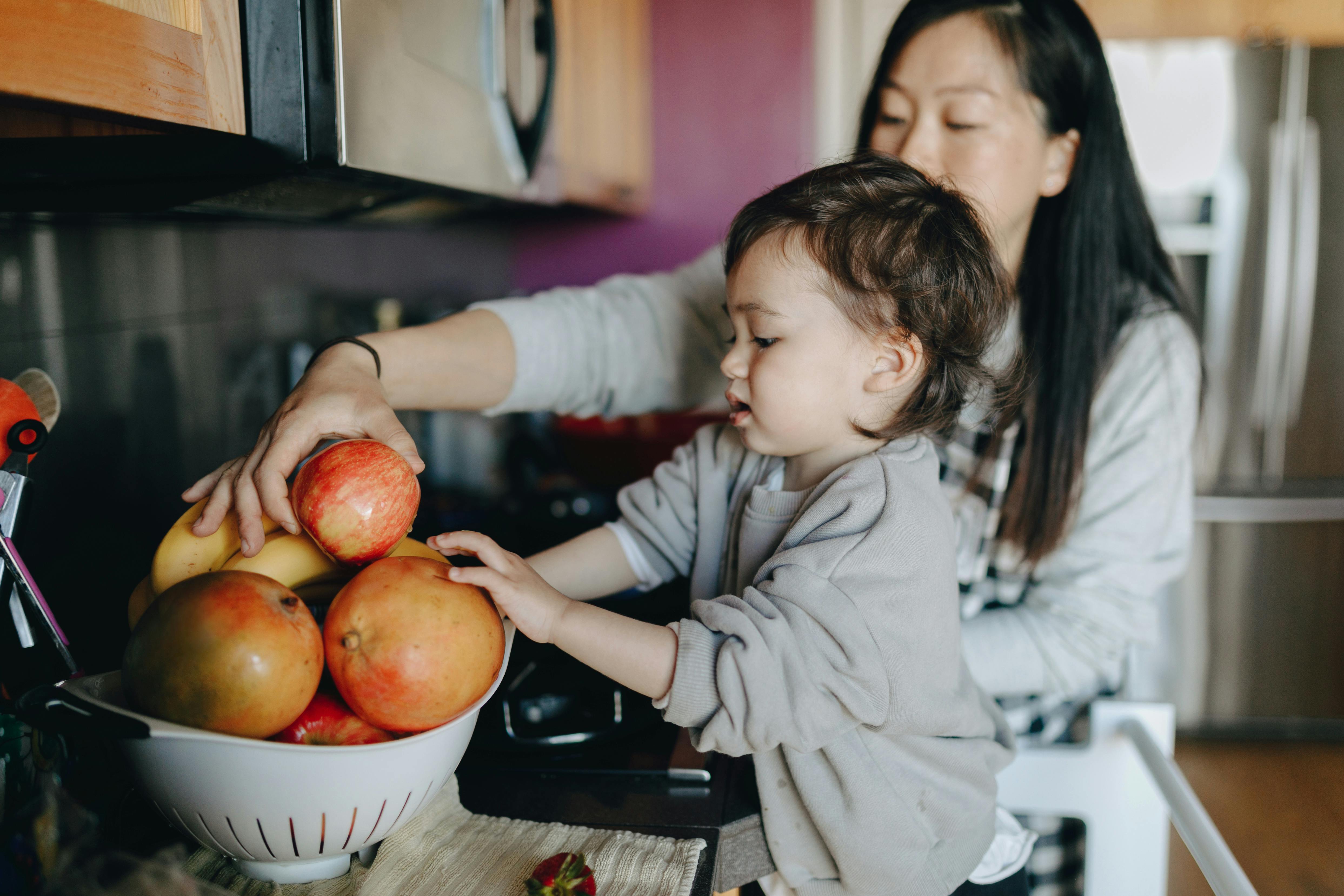Woman and child picking fruits from a bowl | Source: Pexels