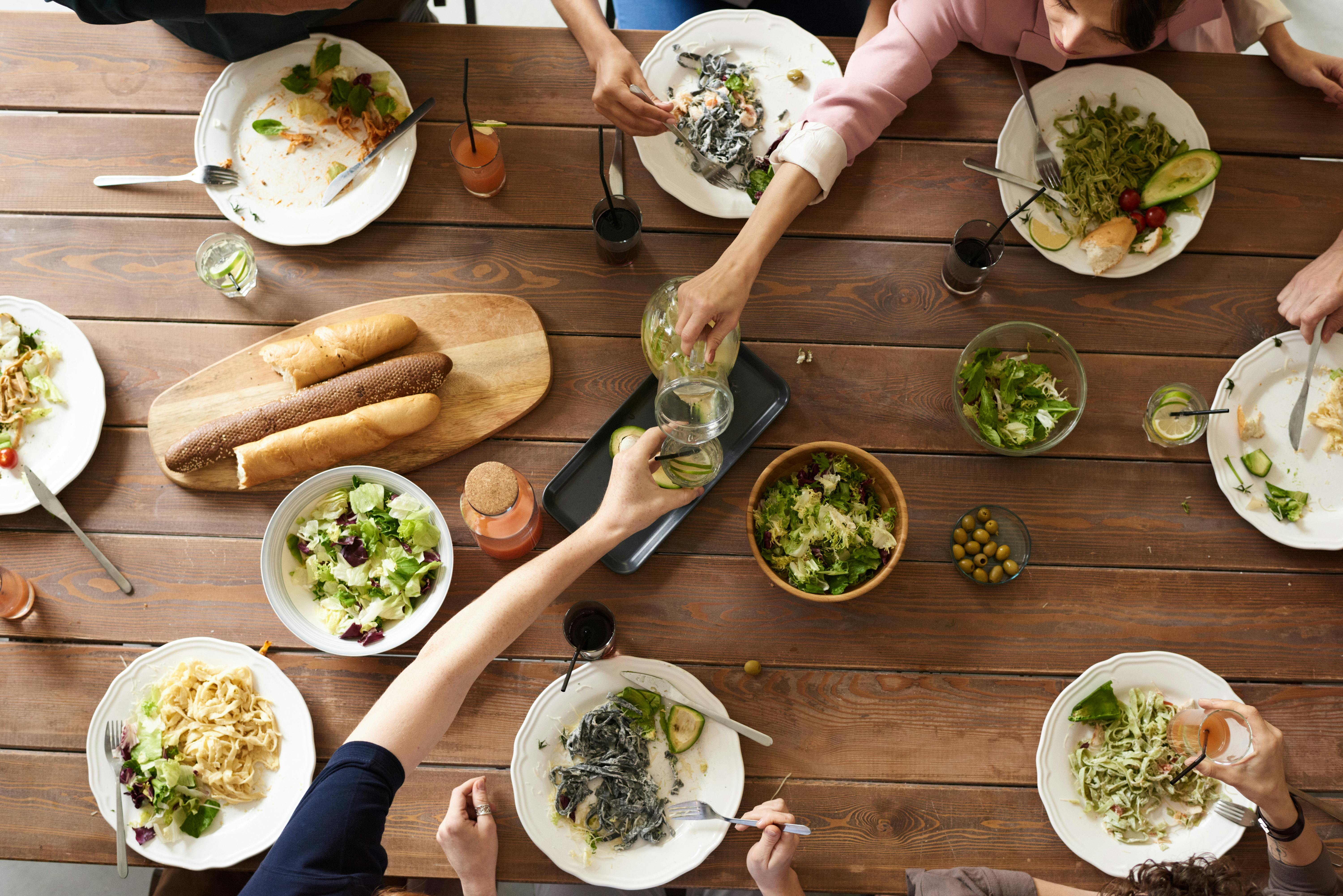 People sharing a fresh, colorful meal around a wooden table | Source: Pexels